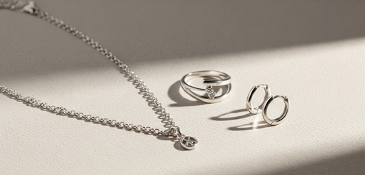 Eine Auswahl an 925 Silberschmuck von Vladura Glam, darunter ein Ring, eine Kette und Ohrringe, elegant auf einem neutralen Hintergrund arrangiert.